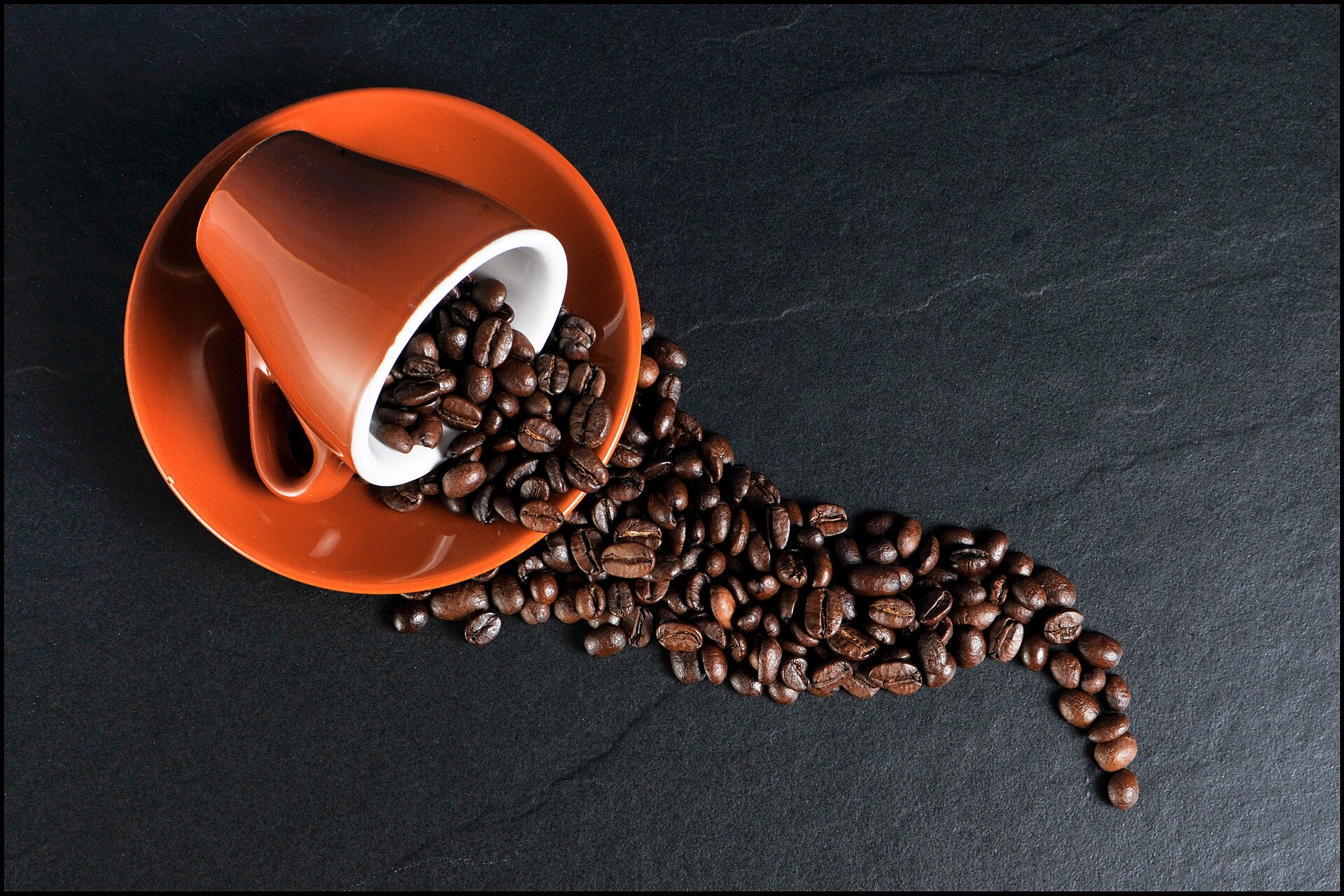 Roasted coffee beans spilling from an orange cup, illustrating the Fresh Roasted Coffee free shipping deal
