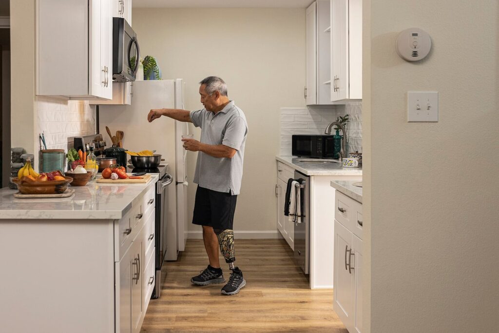 Person cooking in a kitchen with a wall-mounted home alarm visible