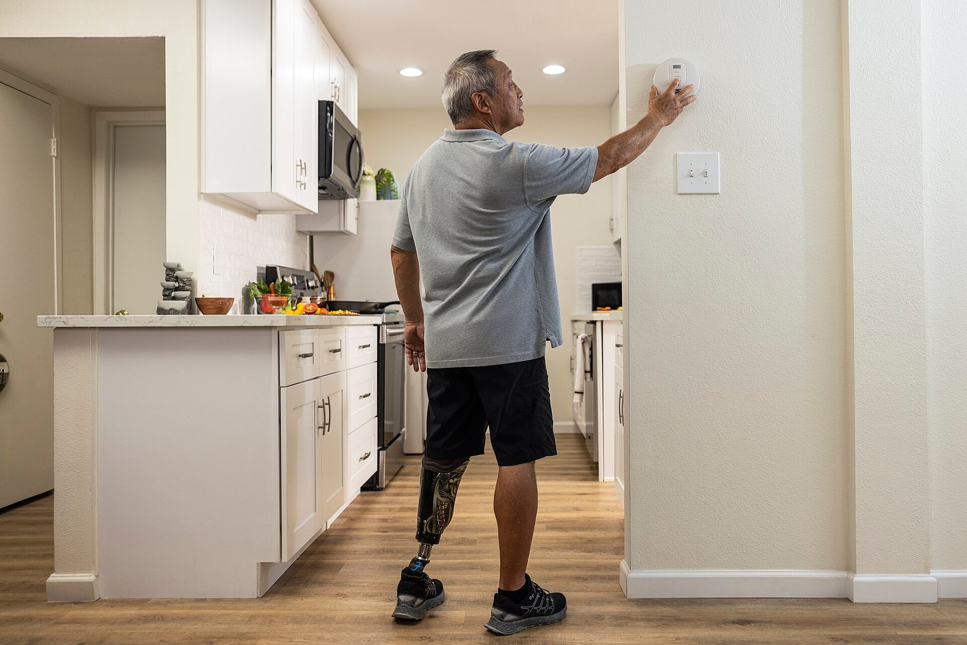 Person testing a home alarm beside a modern kitchen