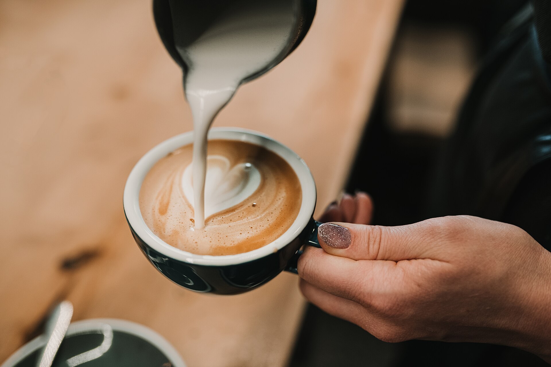 Barista pouring glossy microfoam for a milk coffee