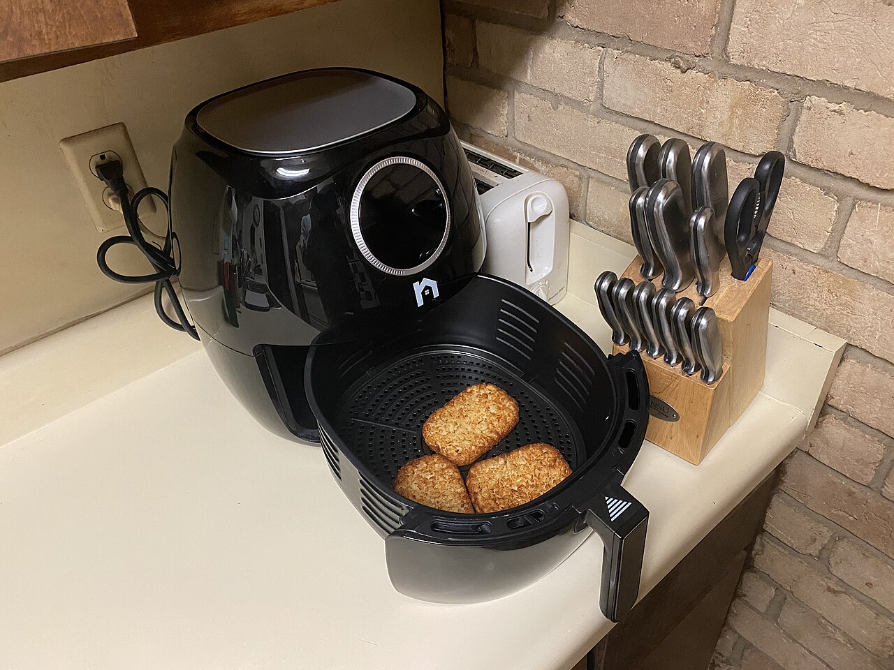Black air fryer with its basket open on a compact kitchen worktop