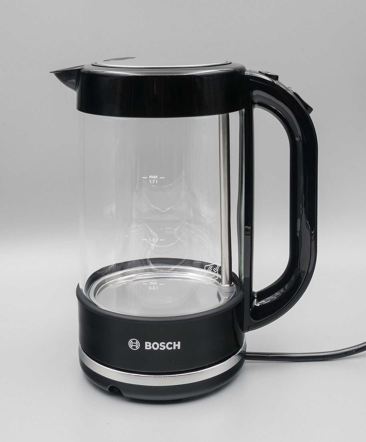 Clear glass electric kettle with a black handle on a neutral background