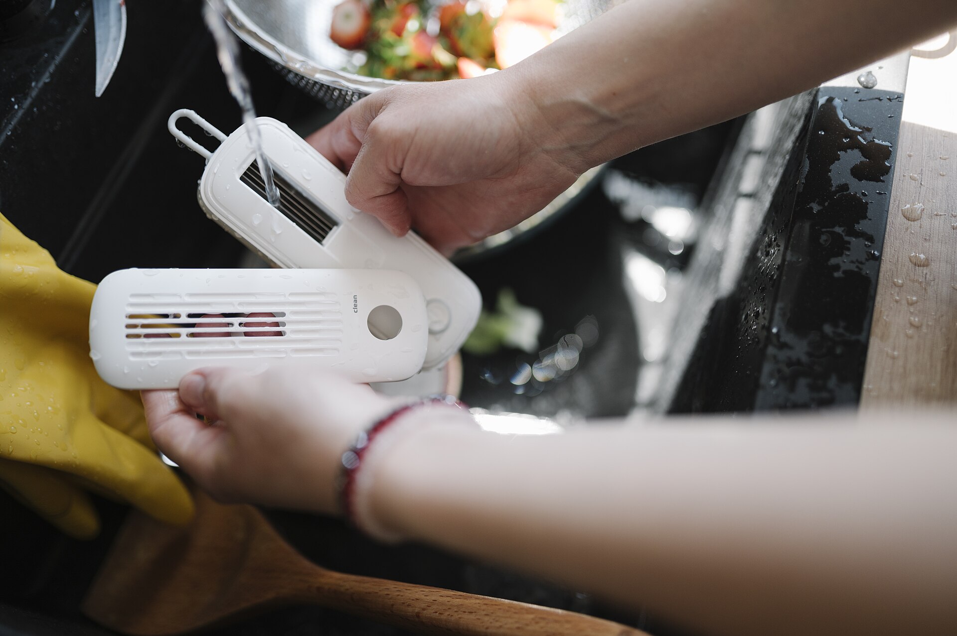 Hands hold kitchen cleaning tools while preparing food at a sink for best kitchen cleaning tools for grease and limescale