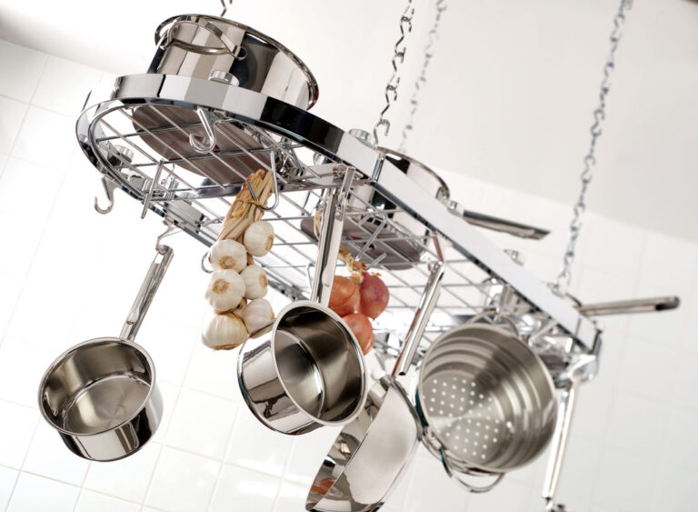 Stainless steel saucepan set hanging from a kitchen rack