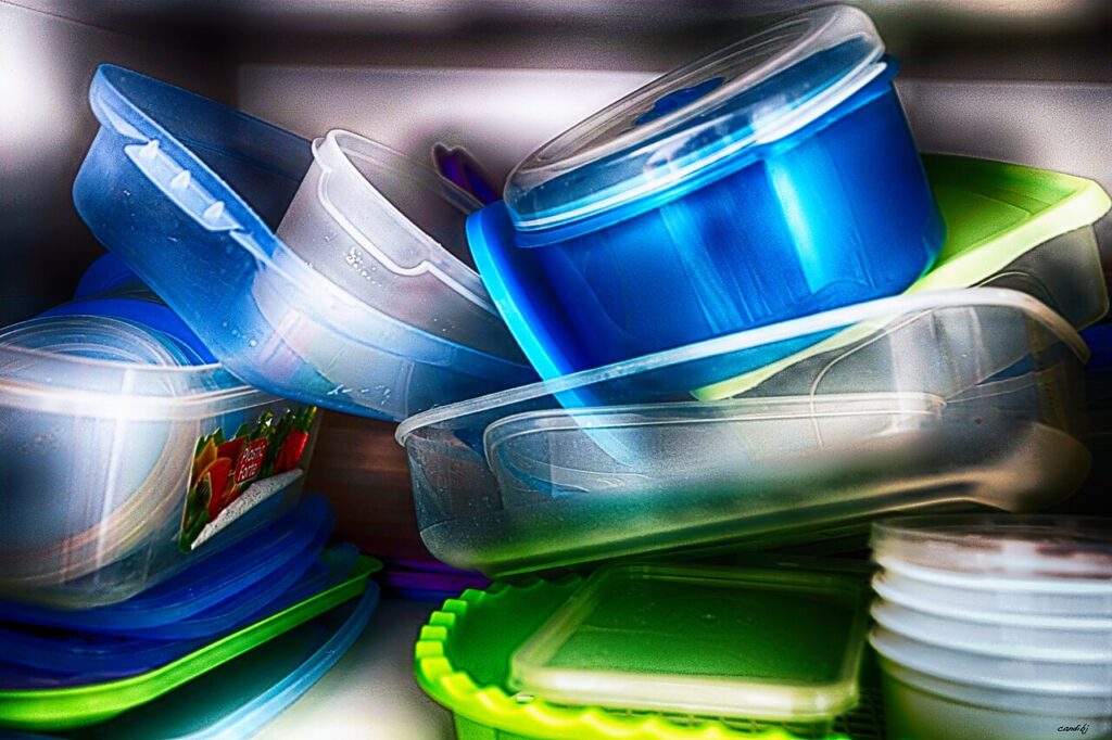 Mixed food containers and lids crowded together in a cupboard