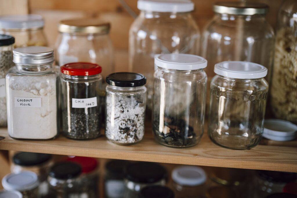 Container storage at a kitchen pantry with different types of food items in jars and bottles at home, illustrating a daily-use detail in glass vs plastic food containers for leftovers