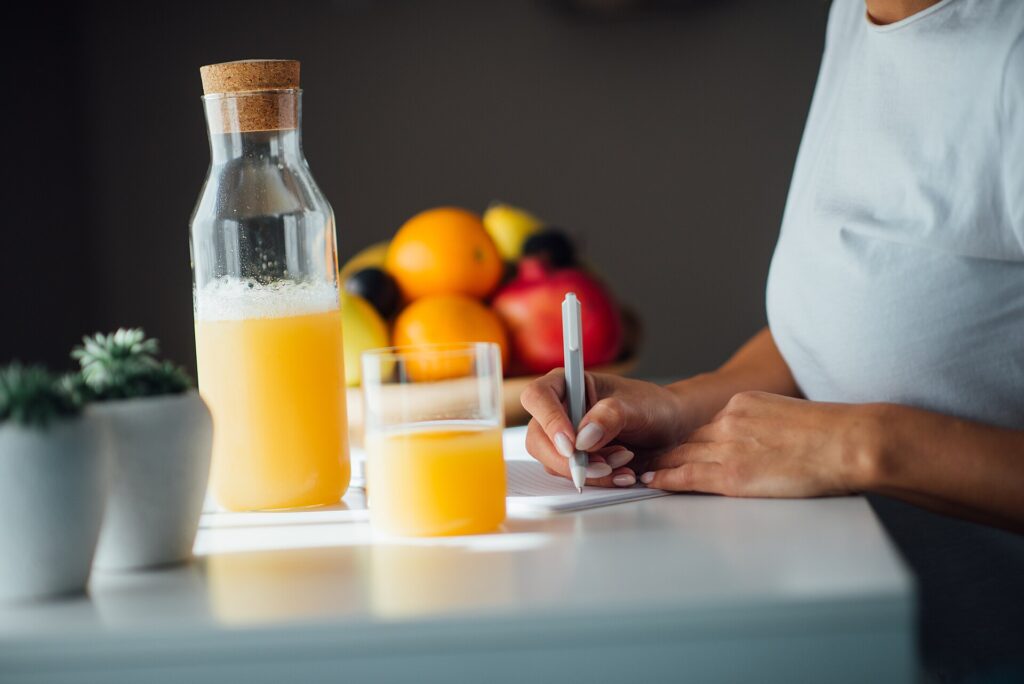 Person writing research notes at a bright kitchen counter