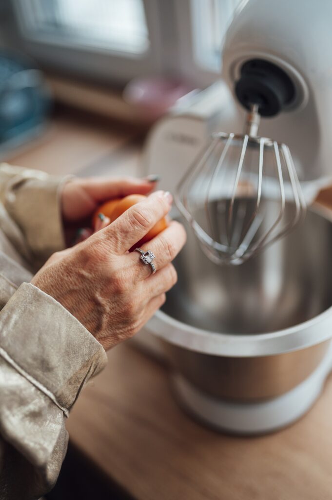 Woman prepares ingredients while using a stand mixer in a modern kitchen, illustrating a daily-use detail in stand mixer vs hand mixer for home baking
